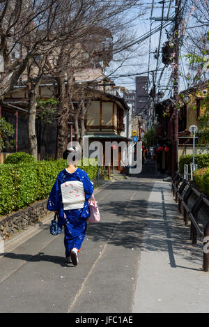 Japonais marchant le long d'une rue étroite, en costume de kimonos traditionnels. Banque D'Images