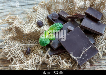 Morceaux et gouttes de chocolat noir naturel sur de vieux sacs. Banque D'Images