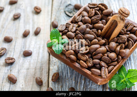 Les grains de café et écope en bois dans un bol. Banque D'Images