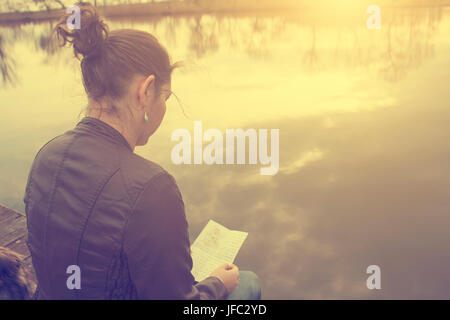 Femme d'apprentissage au coucher du soleil dans le lac d'automne Banque D'Images