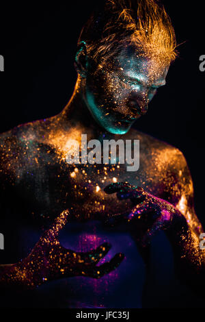 Shot conceptuel de la lumière et l'éclat des couleurs fluorescentes young man's face Banque D'Images