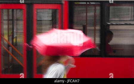 Jeune femme floue sous égide d'exécution à prendre un bus un jour de pluie Banque D'Images