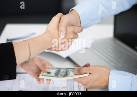 La femme et l'homme handshake close up avec l'argent dans l'autre main. Traiter, la vénalité, corruption, pot-de-concept Banque D'Images