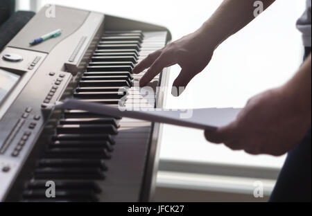 Un seul doigt appuyant sur la touche au piano. Man notes de papier et la formation d'une nouvelle chanson ou une mélodie à partir de la partition. Le pianiste de la rédaction d'un nouveau travail Banque D'Images