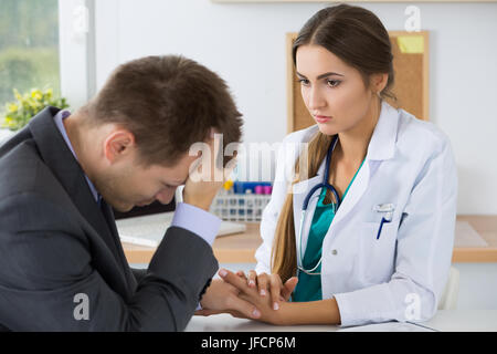 Femme médecin médecine holding business man main d'encouragement pour lui dire de mauvaises nouvelles. Perte relative immédiate, le stress, les maux de tête et service médical Banque D'Images