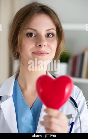 Femme médecin médecine tenir en mains jouet rouge coeur libre. Médecin, thérapeute Cardio cardiaque, faire physique de mesure du rythme cardiaque ou arythmie con Banque D'Images