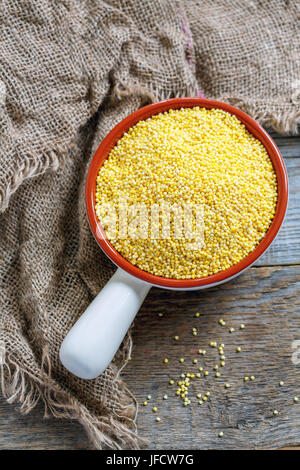 Millet cru dans un bol en céramique. Banque D'Images