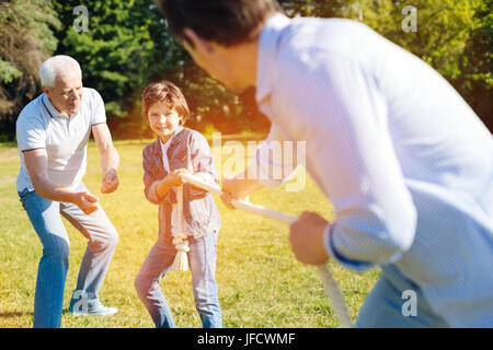 Croyez en vous-même. Soutien intelligent de l'homme donnant son petit-enfant d'un conseil pendant qu'il joue avec son père et en tirant sur la corde Banque D'Images