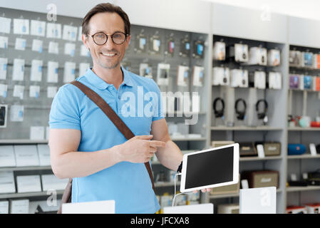 J'ai finalement trouvé le parfait. Occupé homme adultes portant des lunettes shopping pour une nouvelle tablette et en pointant du doigt un gadget alors que la transmission et lookin Banque D'Images