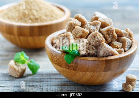 Bol en bois avec cubes de sucre de canne brun. Banque D'Images