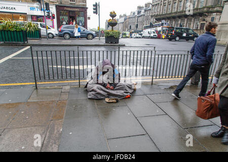 Edimbourg, Royaume-Uni : 27 mai 2016 : un mendiant se trouve dans la pluie sur une jonction occupé à Édimbourg. Il pleut et il est ignoré par les passants. Banque D'Images