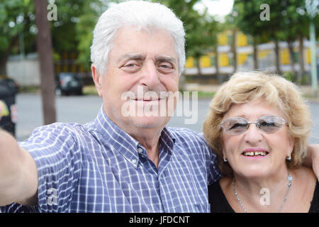 Portrait d'un couple de personnes âgées en tenant l'extérieur selfies. Banque D'Images