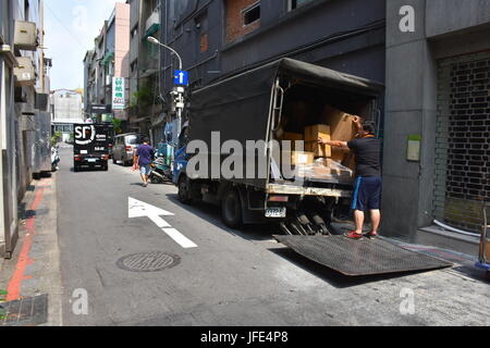 Un camion de livraison parcs sur le côté de la route dans un allié pour décharger des boîtes sur une rue à sens unique, à Taipei, Taiwan. Banque D'Images