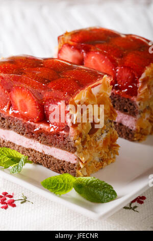 Appétissant morceau de gâteau aux fraises à la menthe fraîche gros plan sur une plaque verticale sur la table. Banque D'Images