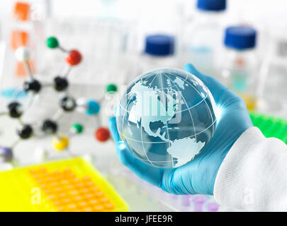 Global research, conceptual image. Scientist holding a globe avec un banc de laboratoire et la verrerie en arrière-plan. Banque D'Images