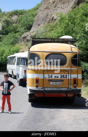 Un petit garçon se tient à côté d'un vieux bus près de guéghard monastère en Arménie Banque D'Images