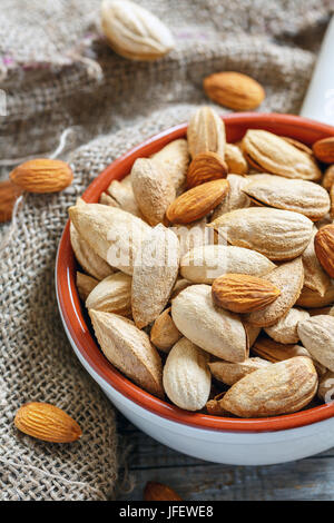 Bol en céramique et les amandes dans une vieille toile de jute. Banque D'Images