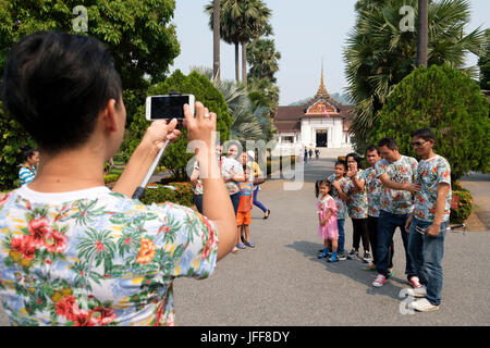 Famille en vacances qui pose pour photo de groupe sur le terrain du Palais Royal, Luang Prabang, Laos, Asie Banque D'Images