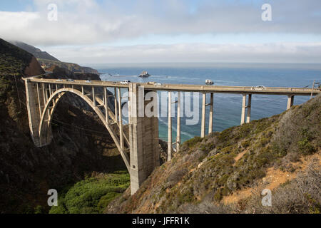 Voitures traversant le pont du ruisseau Bixby, un béton, pont en arc de tympan ouvert, sur l'Autoroute de la côte Pacifique. Banque D'Images
