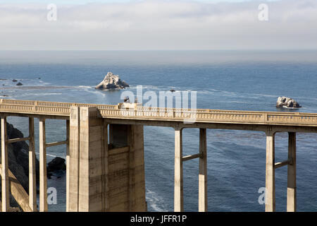 Plusieurs personnes assises et des visites sur le pont du ruisseau Bixby, un béton, pont en arc de tympan ouvert, sur l'Autoroute de la côte Pacifique. Banque D'Images