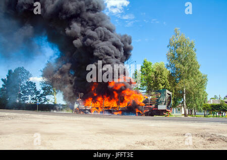 Chariot en feu avec fumée noire sur la route Banque D'Images