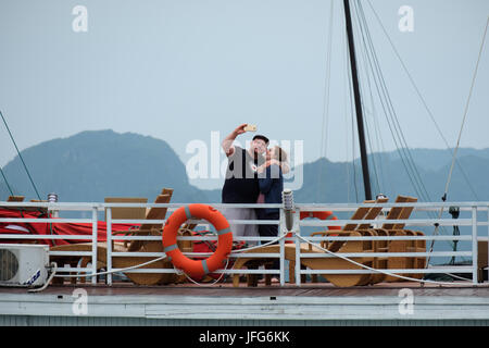 Les touristes en tenant vos autoportraits en montant sur un bateau d'excursion à la baie d'Halong, Vietnam, Asie Banque D'Images