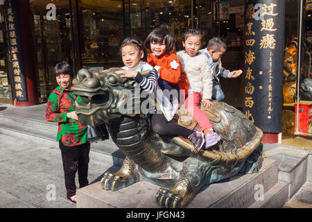 La Chine, Shanghai, le Jardin Yuyuan, les enfants jouant sur la tête du Dragon de bronze statue Tortue Banque D'Images