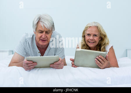 Couple using digital tablets tout en vous relaxant dans la chambre Banque D'Images