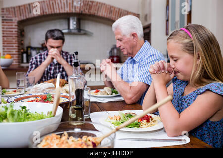 Multi-generation family priant avant having meal Banque D'Images