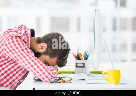 Hipster homme assis à un bureau d'ordinateur est fatigué Banque D'Images