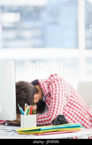 Hipster homme assis à un bureau d'ordinateur est fatigué Banque D'Images