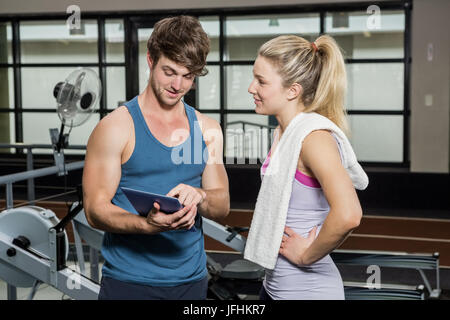 Formateur à l'aide d'une tablette numérique tout en parlant à une femme Banque D'Images