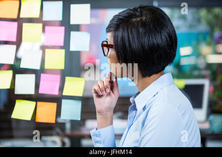 Thoughtful businesswoman looking at sticky notes Banque D'Images