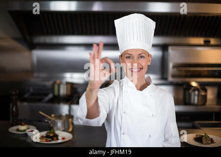 Portrait of smiling female chef showing ok sign Banque D'Images