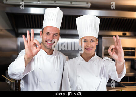 Portrait of happy chefs montrant des signes ok dans la cuisine Banque D'Images