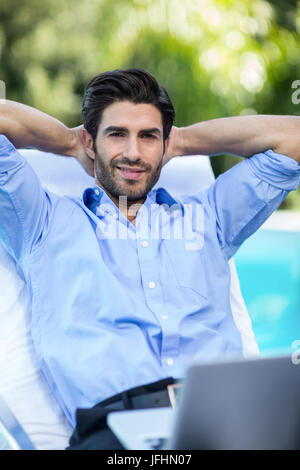 Homme intelligent avec un ordinateur portable de vous détendre sur une chaise longue Banque D'Images