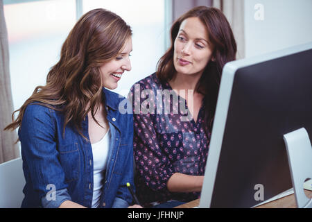 Deux femmes en interaction les uns avec les autres en face de l'ordinateur Banque D'Images