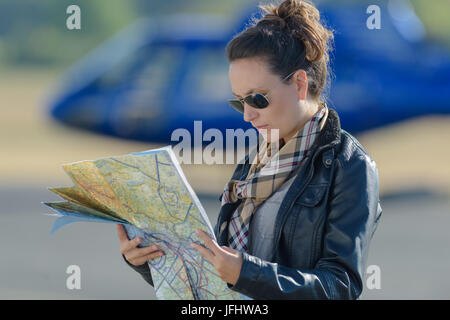 Woman looking at map, hélicoptère en arrière-plan Banque D'Images