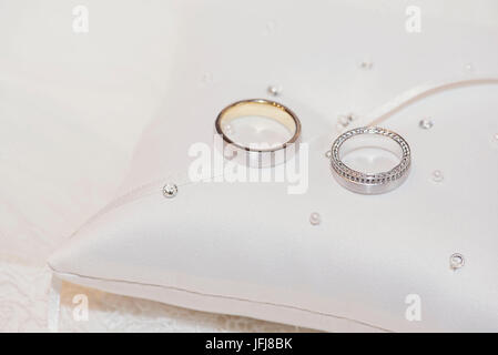 Les alliances en or et platine avec des diamants sur un petit coussin de perles Banque D'Images