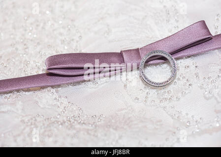 Anneau de platine avec diamants et ruban mauve sur un fond fait de Lacy Banque D'Images