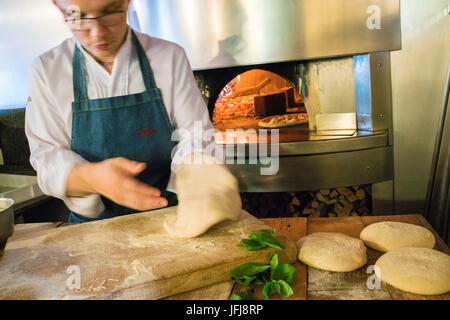 La pâte à pizza a travaillé par le chef prêt à être farci avec des ingrédients frais et cuits dans le four à bois Italie Banque D'Images