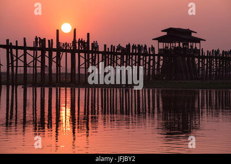 Amarapura, région de Mandalay, Myanmar, Silhouetté personnes marchant sur le pont U Bein au coucher du soleil, Banque D'Images