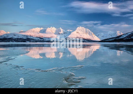 Bleu ciel et les sommets enneigés se reflètent dans le lac gelé Jaegervatnet Stortind Tromsø Alpes de Lyngen Norvège Laponie Europe Banque D'Images