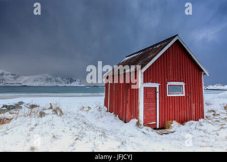 Une maison typique des pêcheurs appelée sur la plage enneigée rorbu cadres la mer glacée à Ramberg Lofoten, Norvège Europe Banque D'Images