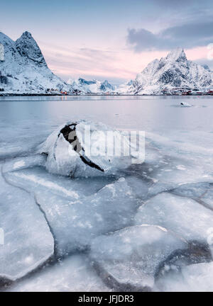 La mer gelée et les cimes enneigées du village de pêcheurs de trame au coucher du soleil Reine Nordland îles Lofoten Norvège Europe Banque D'Images