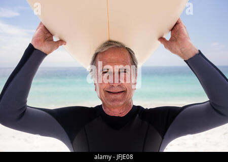 Portrait of senior man holding a surfboard sur sa tête Banque D'Images