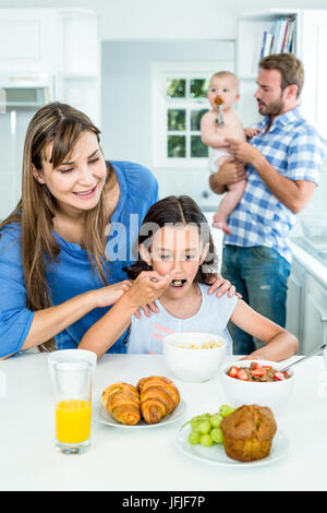 Smiling mother à la fille à prendre le petit déjeuner dans la cuisine Banque D'Images