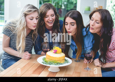 Les amis soufflé les bougies sur un gâteau d'anniversaire Banque D'Images