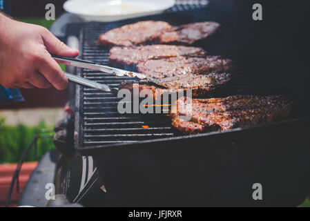 La cuisson des steaks sur le gril. Banque D'Images