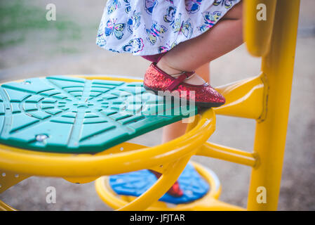 Une jeune fille marche dans un trottoir de derrière au coucher du soleil à l'automne portant une cape rouge. Banque D'Images